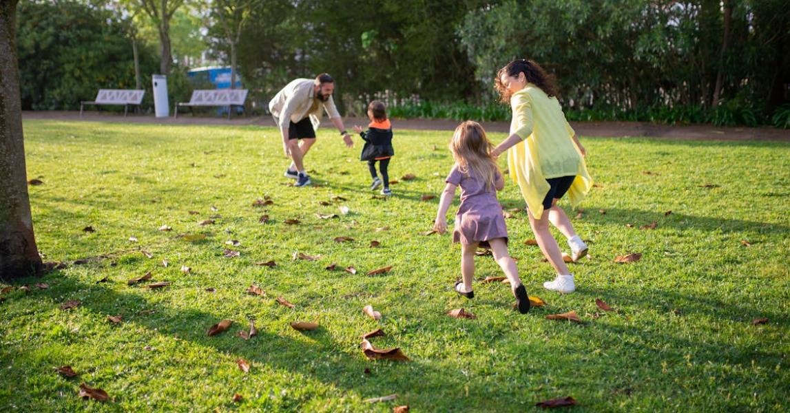 A mother and farther playing with two young children in the park